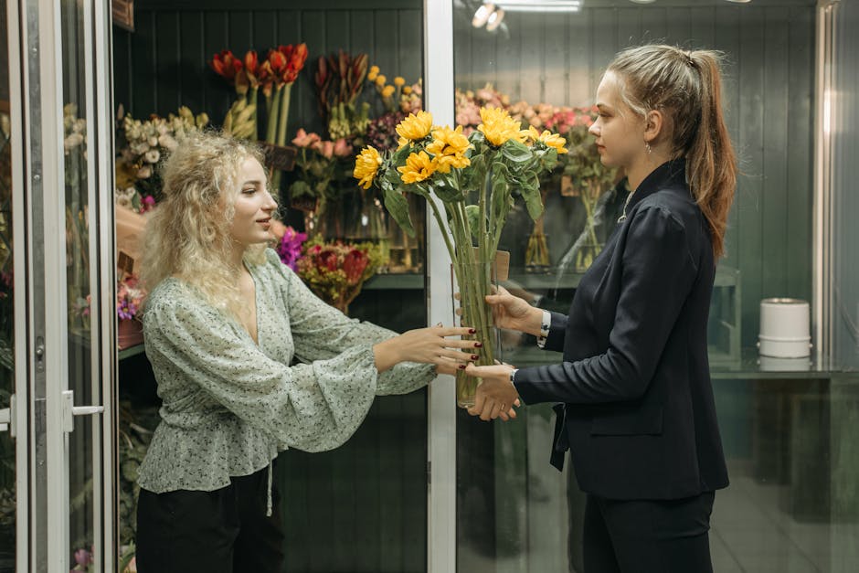 A vibrant floral bouquet featuring a large, white and lavender chrysanthemum as the central flower, complemented by a delicate, peach-pink rose and smaller white and purple blooms, all arranged with l