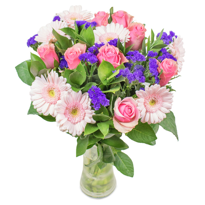 A vibrant bouquet featuring a lush arrangement of about eight pink roses and six soft pink Gerbera daisies stands proudly in a crystal-clear glass vase, as if freshly placed on a Rush Green windowsill. Each rose, whether tightly closed or gently unfurling, displays the intricate spiral formation unique to the classic variety, imbuing the bouquet with understated luxury. The Gerberas, larger in size, offer their trademark round, radiating petals and near-white centers-each bloom echoing the gentle pink hues that run through Rush Green's spring gardens. Interwoven throughout are bold clusters of deep purple statice, lending memorable texture and dynamic pops of colour reminiscent of blooms seen along Eastern Avenue's paths. Supporting these primary flowers is rich, abundant green foliage, forming a dense and thoughtful base while suggesting a thriving garden. The clear glass vase, with water refracting the stems and enhancing the blooms' lively freshness, grounds the design with natural elegance. Crafted by a skilled local florist, this arrangement is perfect for milestones such as birthdays, anniversaries, or as a sophisticated uplifting accent for a Rush Green home or workspace. Each element feels deliberate and meaningful, blending sensory delight with emotional connection and capturing the spirit of the local community's green spaces and bright mornings.