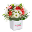 Brimming with light and joy, this vibrant bouquet evokes the feeling of a fresh spring morning in Rush Green. Generous clusters of coral and peach carnations burst with sumptuous, frilled petals, drawing the eye alongside cheerful white daisies crowned with sunny green centers. Sprigs of baby's breath float delicately throughout, their cloud-like presence infusing the arrangement with a sense of gentle innocence. Along the side, a few purple-tinted buds peek out, creating a subtle sense of curiosity and possibility-a quiet echo of wildflowers spotted on walks through Rush Green's quiet corners. The flowers are embraced by a cascade of deep green, glossy leaves, which cradle the arrangement in a natural flourish. All are gathered in a crisp, white square gift bag, complete with white ribbon handles for ease of gifting or delivery across local postcodes. Soft, even lighting ensures every detail is luminously presented, from the texture of ruffled petals to the sheen of each leaf. This expertly arranged bouquet feels uplifting and sincere-perfect for marking a birthday, sending congratulations, or simply delivering a spark of happiness to someone in Rush Green. It's a testament to the craftsmanship and thoughtful care that defines the area's local florists.